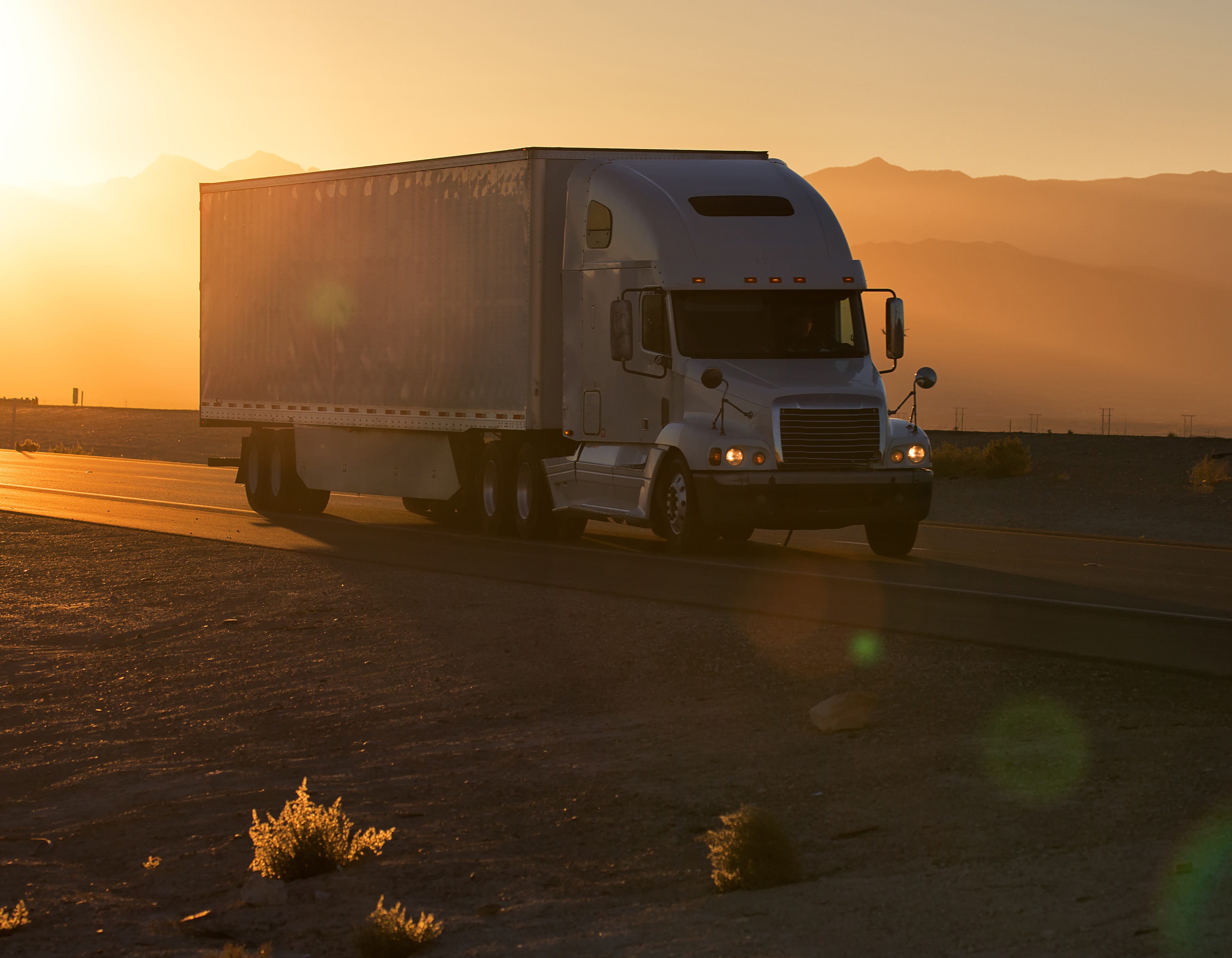 Semi truck driving at sunset