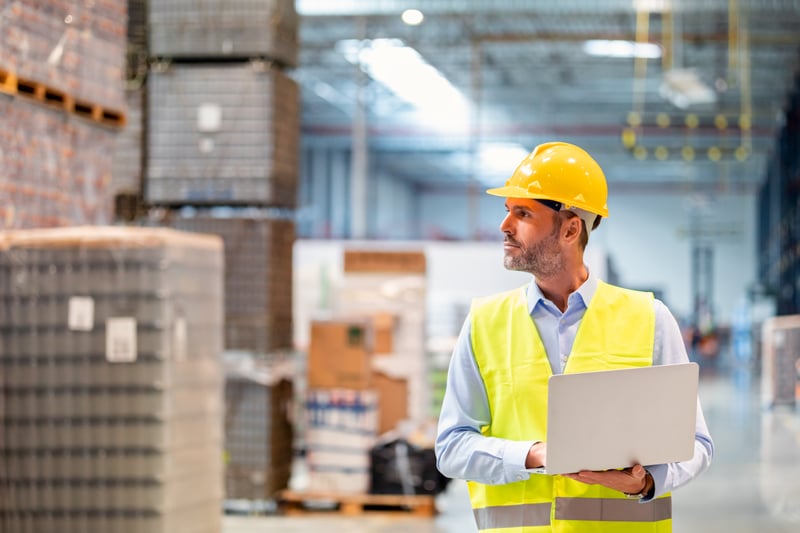 Staff using laptop with cargo in the background