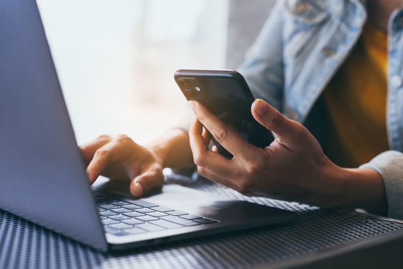 Person using laptop and phone for payment