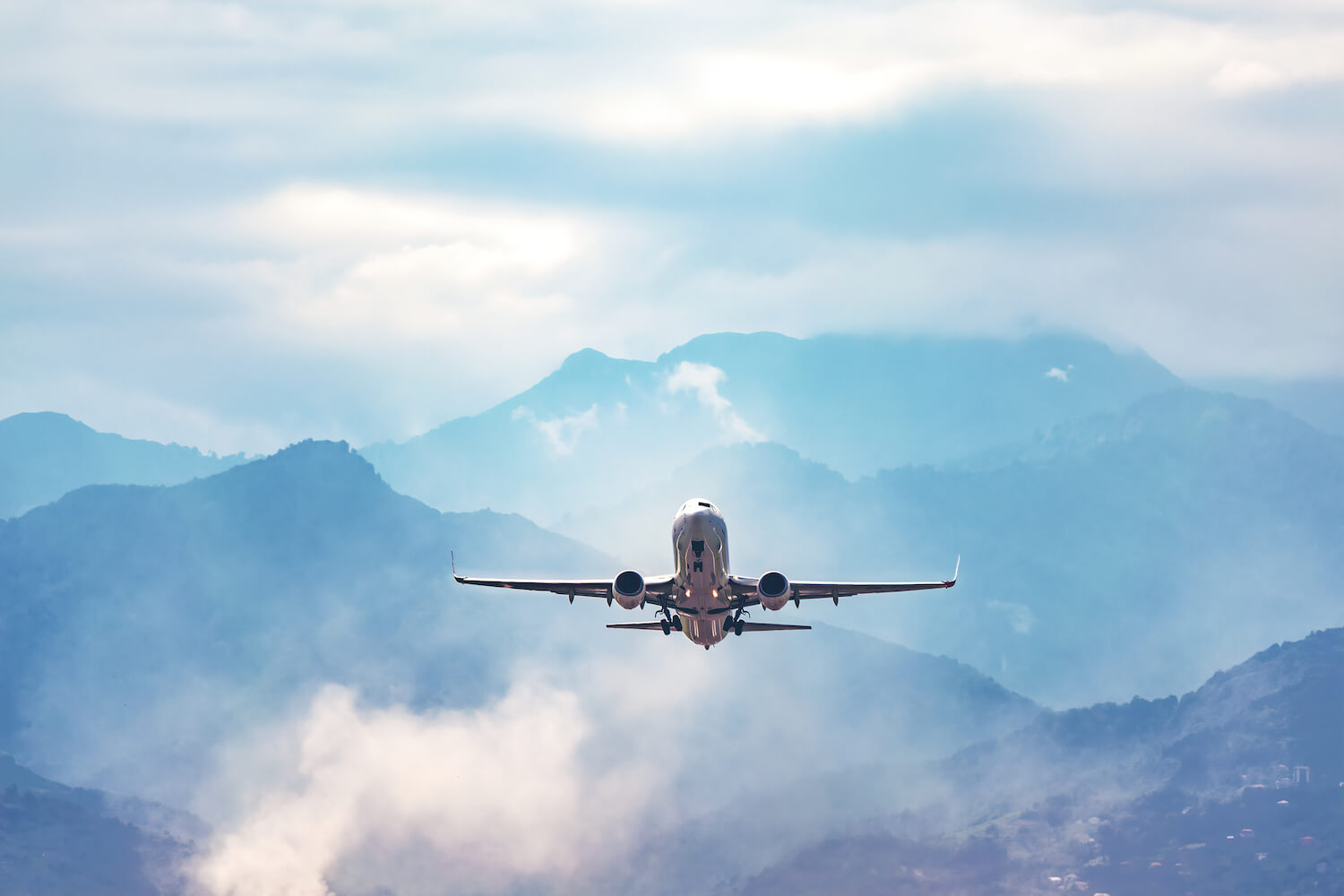 Airplane flying in the sky with mountains in the background