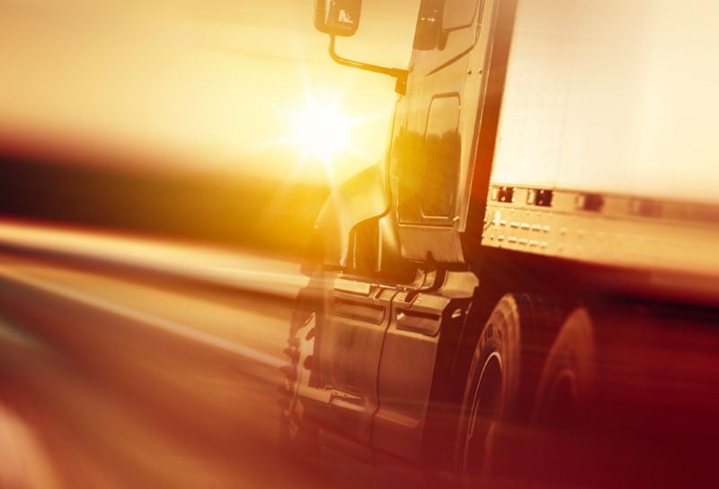 Tractor trailer driving on the road at sunrise